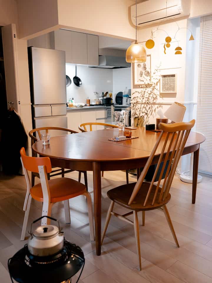 木目調とゴールドが調和するダイニング、アーコールのゴールドスミスチェアと木製ダイニングテーブルを配した雰囲気のある空間