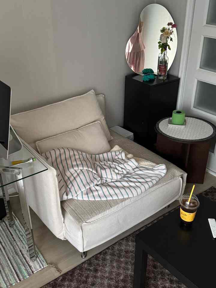 ホワイトとブラックのトーンのワンルームリビング、モダンなソファとタイルのサイドテーブル、不規則な形の鏡が配置された落ち着いた空間