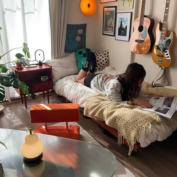 ホワイトのベッドと木目調家具が配置された8畳のワンルーム、読書を楽しむ自然な北欧スタイルの雰囲気あるインテリア