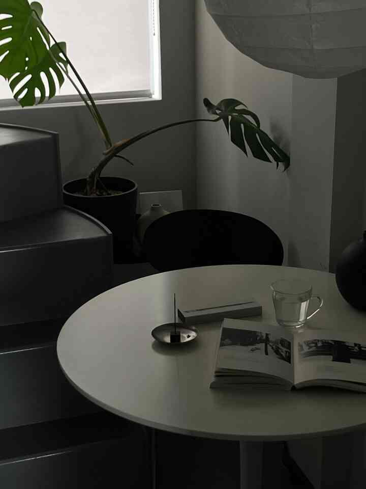 シンプルでホワイトトーンの円形の部屋、丸いダイニングテーブルと読書用の本が配置された落ち着いた空間