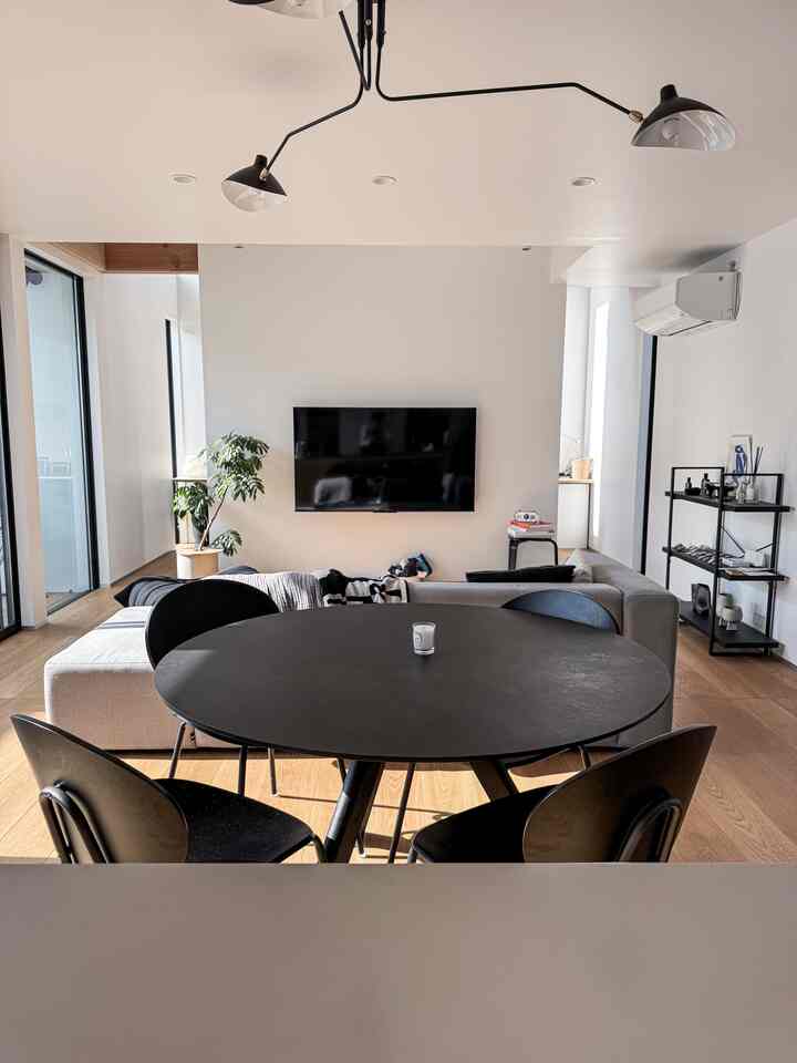 ブラックとブラウンのリビング、円形のダイニングテーブルと大きなソファが配置されたモダンなインテリア