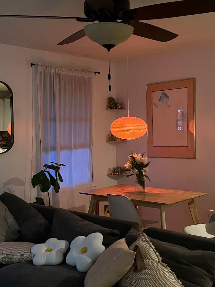 Dark gray sofa and wood tone dining table in a simple modern living room with warm lighting and clean interior