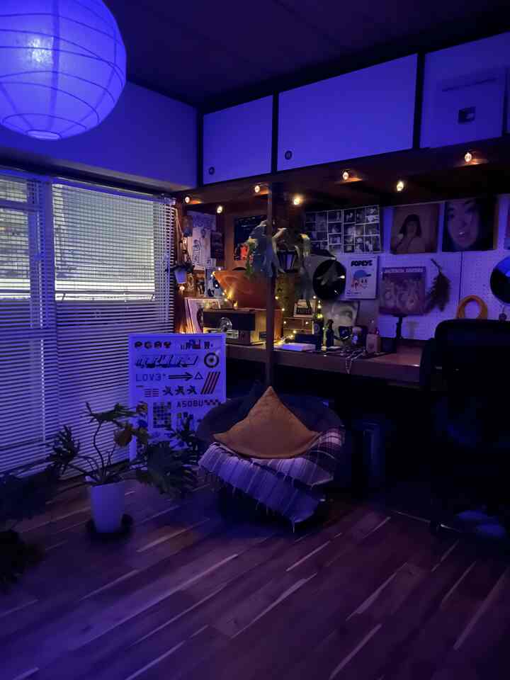 ライトグレーと木目調の小さな寝室、デスクとアームチェアが配置された雰囲気のあるナチュラルインテリア