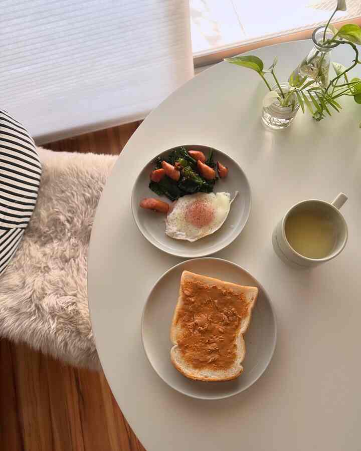 白を基調とした円形のダイニングテーブルとベージュの毛足の長い椅子が配置された、清潔感のあるおうちカフェの朝食空間