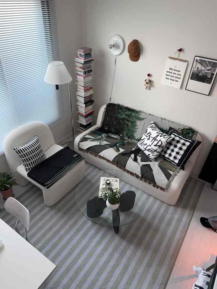 白とグレーのトーンのホームオフィス、ソファとヴィンテージ風クッション、ラグが配置された雰囲気ある空間