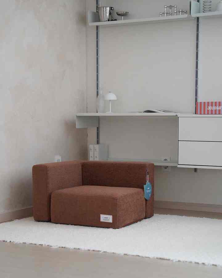 Natural beige and brown toned living room featuring a brown sofa and white textured rug in a modern, simple setting