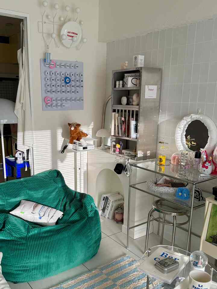 白と緑の色調の狭い部屋、ビーンバッグソファとステンレスの化粧台が配置されたモダンで整ったおうちカフェ空間