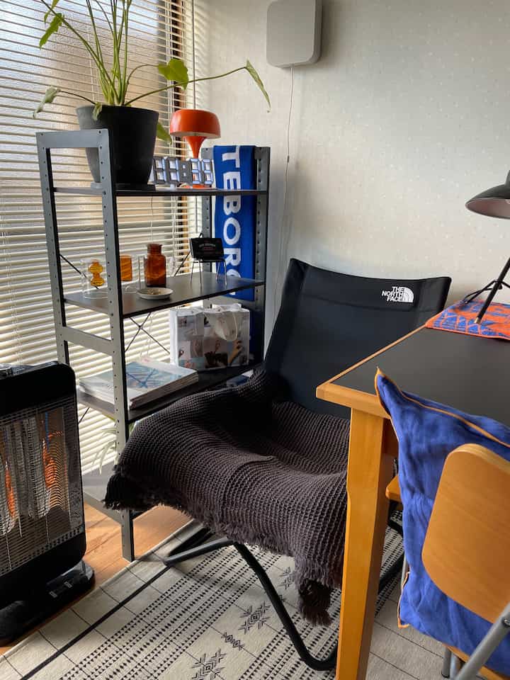 黒いキャンプチェアと木目調のデスクが配置されたコンパクトな在宅勤務スペース