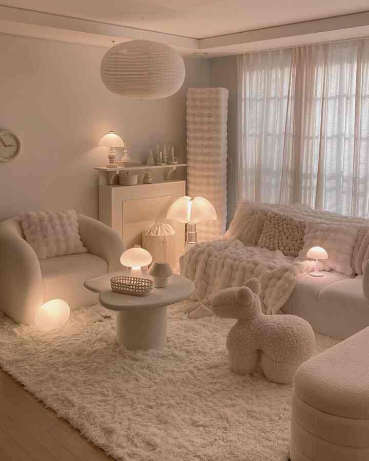 柔らかなアイボリー色調のリビング、コーナーソファとシャギーラグ、多様な照明が調和した暖かく居心地の良い空間