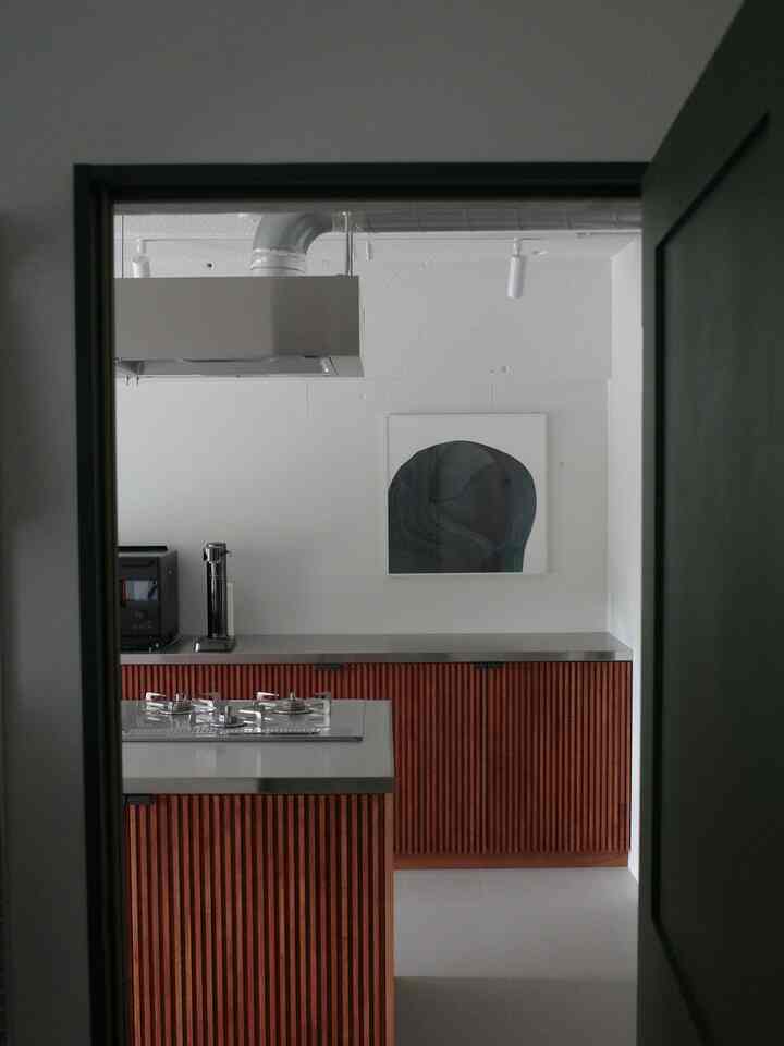 ブラウンの木目調キッチン、中央にキッチンアイランドとステンレスのカウンター、モダンな印象のインテリア