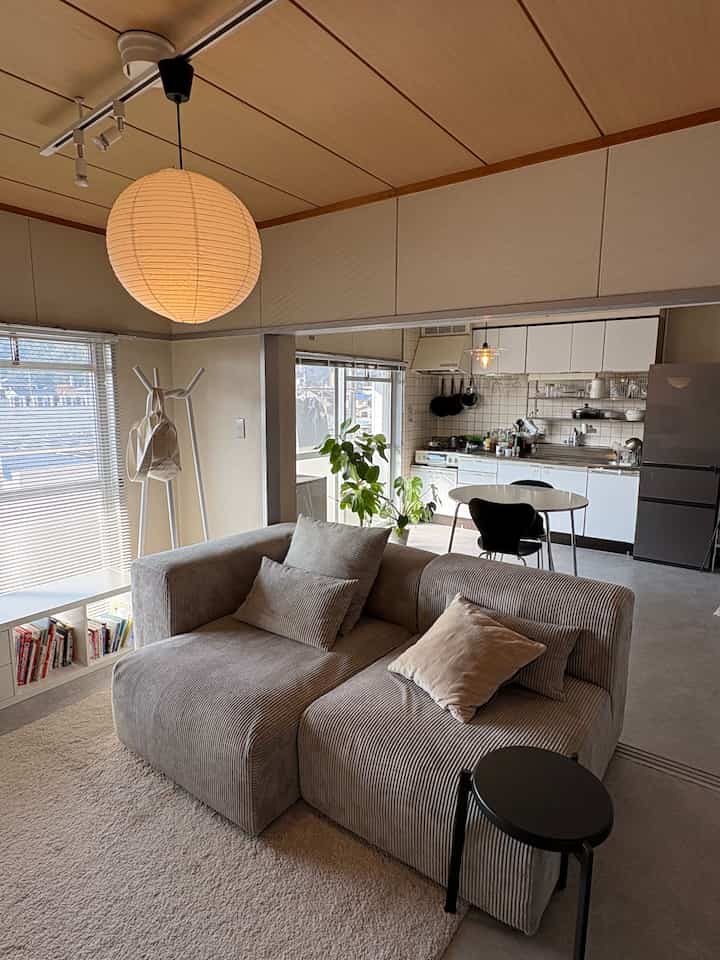 Beige and gray toned living room and kitchen for two-person household featuring natural interior elements and pendant lighting