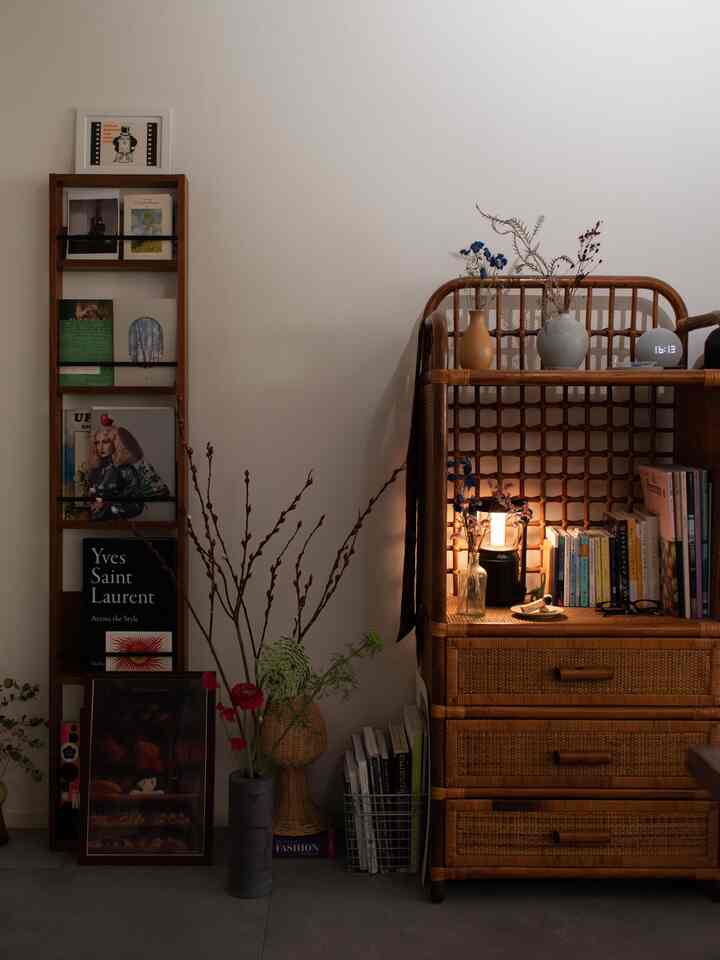 ブラウンとホワイトのトーンが特徴の小さな部屋、木製の本棚と花瓶が配置されたナチュラルモダンなインテリア