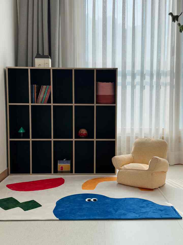 Bright white and black contrasting kids' room featuring a yellow check armchair and colorful rug with a cozy atmosphere