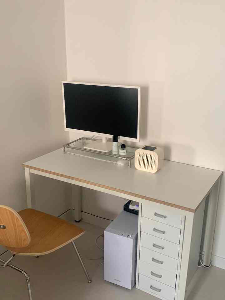 ホワイトとクリーム色調のシンプルでミニマルなワークスペース、デスク上にミニ空気清浄機とモニターが配置された整ったインテリア