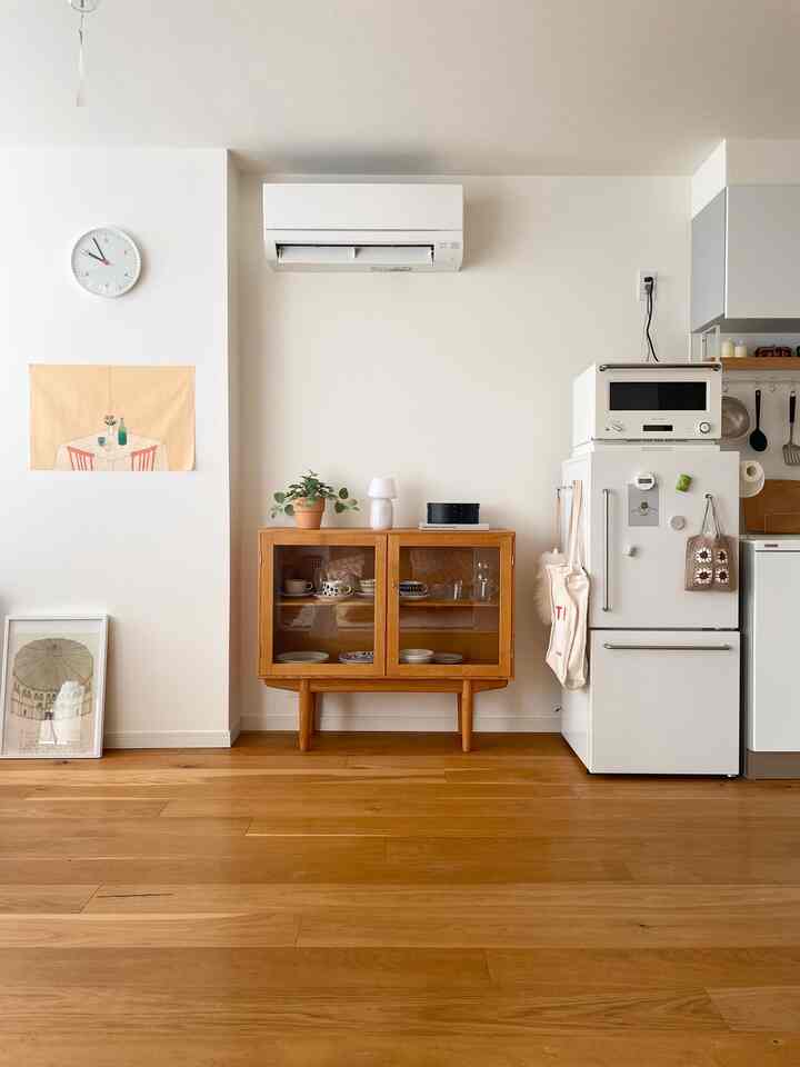 白い壁とブラウンの木目調キャビネットが配置されたナチュラルなリビングのインテリア