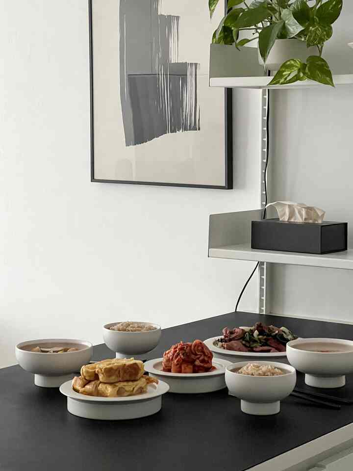 黒と白のトーンでまとめられたモダンでシンプルなダイニング、整然と並べられた食器と料理が置かれたテーブルのある印象的な空間