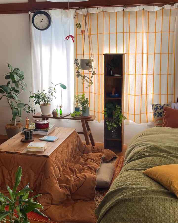 オレンジ色のカーテンとこたつが配置された、植物のあるナチュラルな一人暮らしのリビング