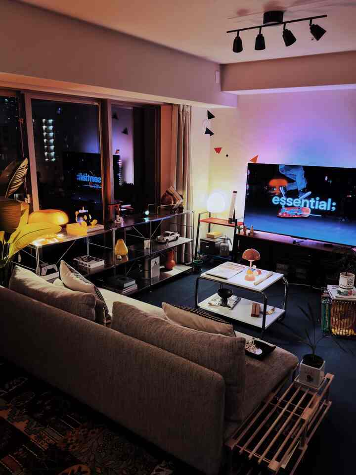 Light gray toned Korean interior living room featuring sectional sofa, TV, and layered lighting creating a cozy atmosphere