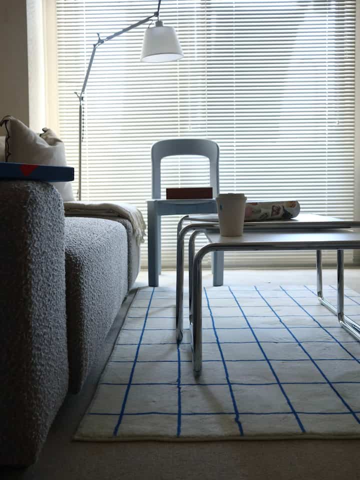 Monotone living room with gray sofa, white blinds, and coffee tables arranged to create a calm atmosphere