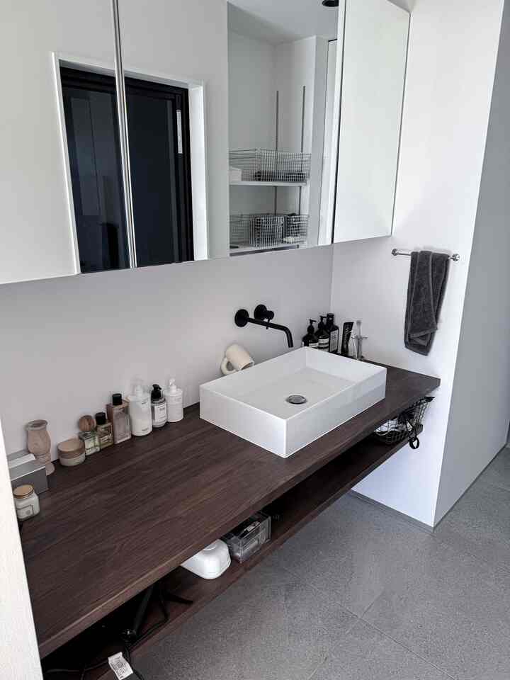 A simple modern bathroom space featuring white walls and a brown wood-tone sink counter
