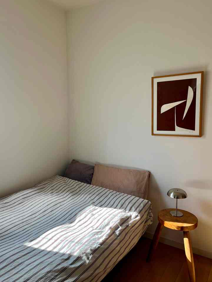 Natural color and wood tone bedroom featuring a simple side table and art poster in a clean, minimal space