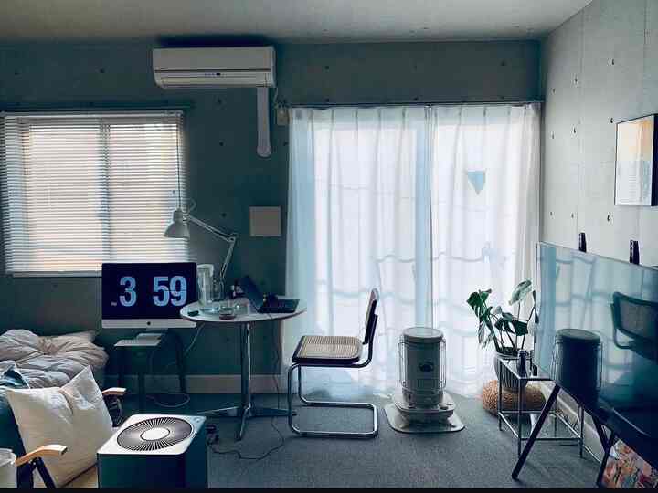 Gray and beige toned two-person bedroom with modern furniture and home office setup, featuring curtains and a cozy atmosphere