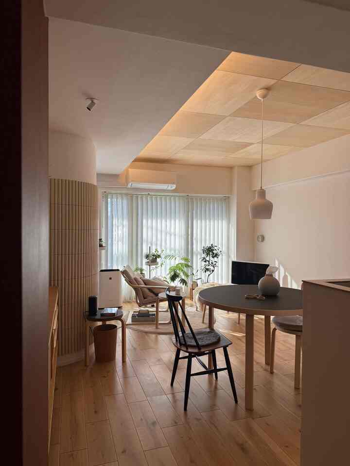 Natural toned living and dining area featuring wood flooring, dining table, and plants in a cozy modern interior