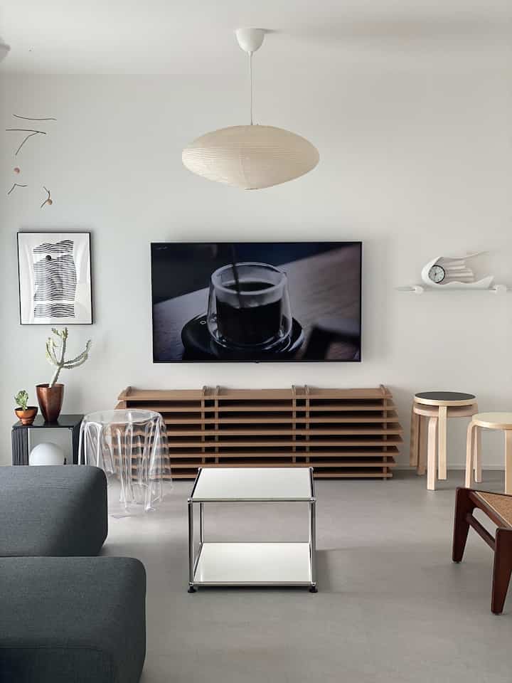 モノトーンとナチュラルウッドの色調のリビング、テレビ台とソファが配置された印象的なミニマル空間