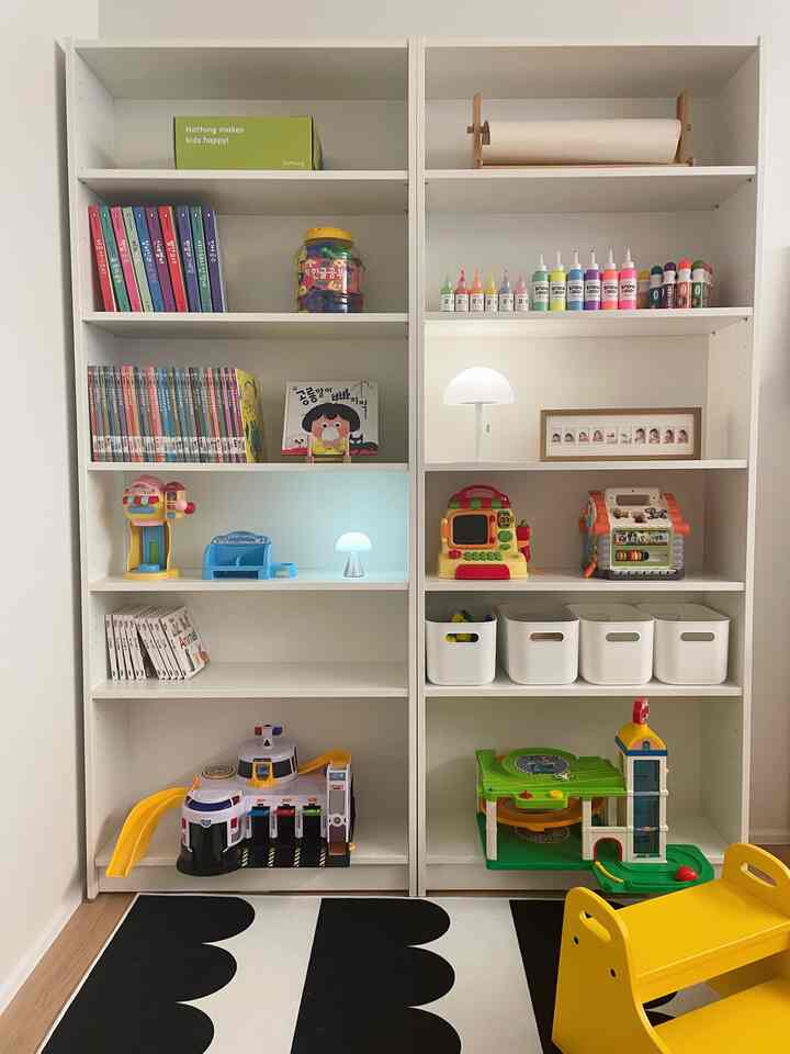 白と黄色の色調の子供部屋、ビリー本棚とスツール、おもちゃと本が整然と並べられた落ち着いた空間