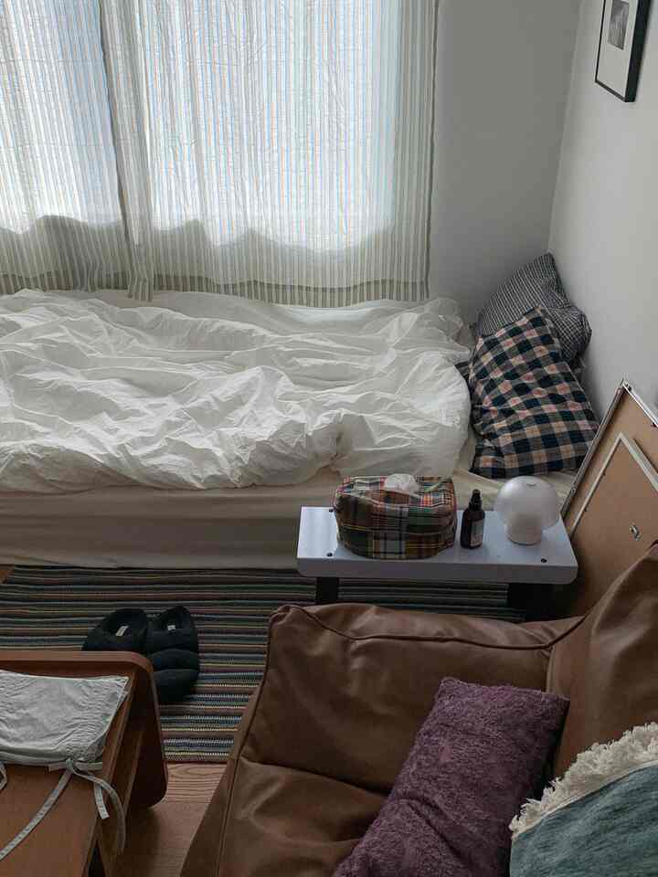 ネイビーとブラウンの色調の寝室、白い掛け布団とチェック柄の枕が調和した落ち着いた雰囲気のインテリア