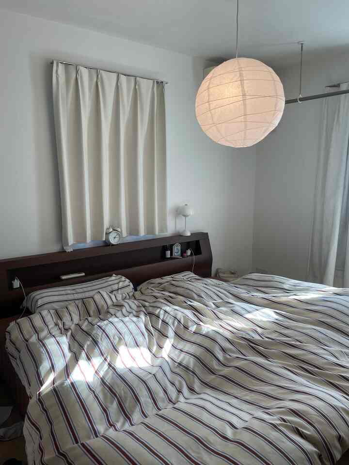 白と茶色のトーンの寝室、大きなベッドとカーテンが配置された落ち着いた雰囲気のインテリア