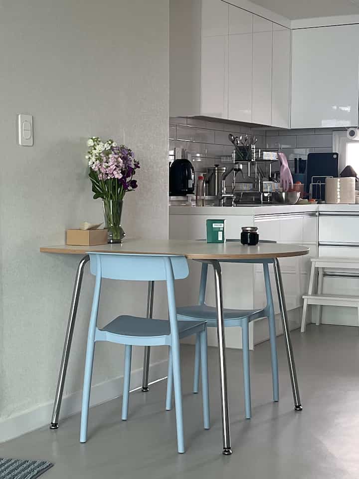 White and blue toned kitchen with compact dining table arranged in a simple cafe style space