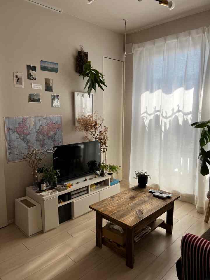 ナチュラルな木目調と白いカーテンの北欧風リビング、ローテーブルとテレビ台が調和した空間