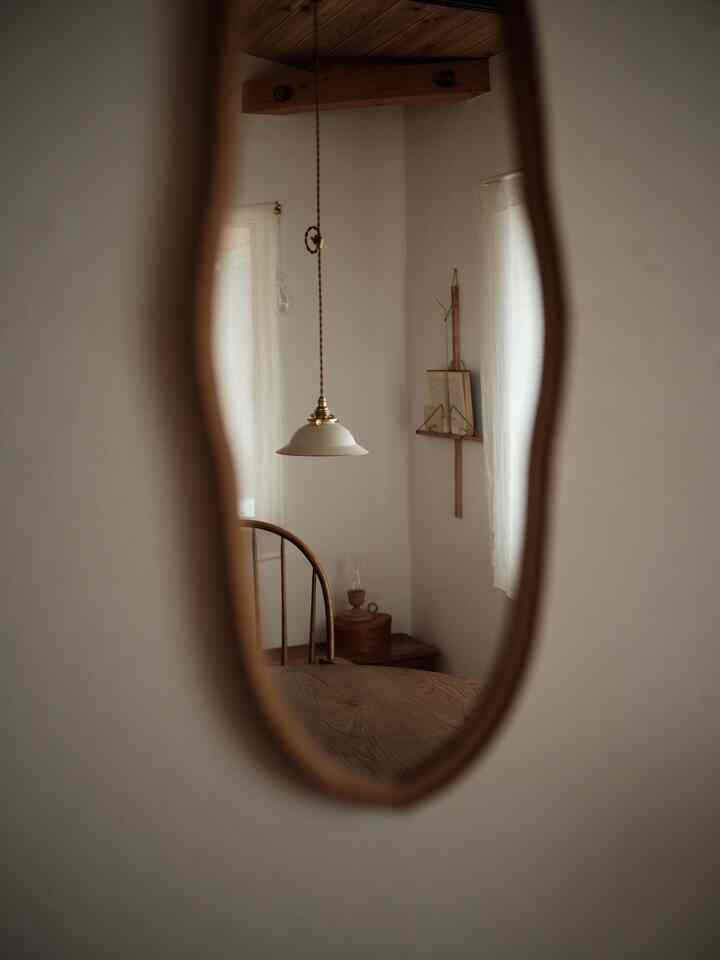 柔らかなブラウンとホワイトの色調のリビング、木材の家具とアンティークのペンダントライトが配置された温かみのある空間