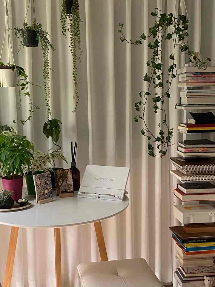 ナチュラルな色調のリビング空間、白い丸テーブルと多様な植物が配置された落ち着いた雰囲気のインテリア