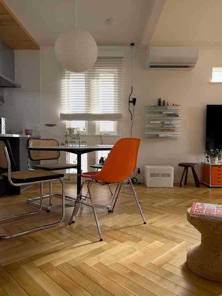 白と木目調のダイニング、オレンジのチェアがアクセントの自然でモダンな雰囲気のあるインテリア