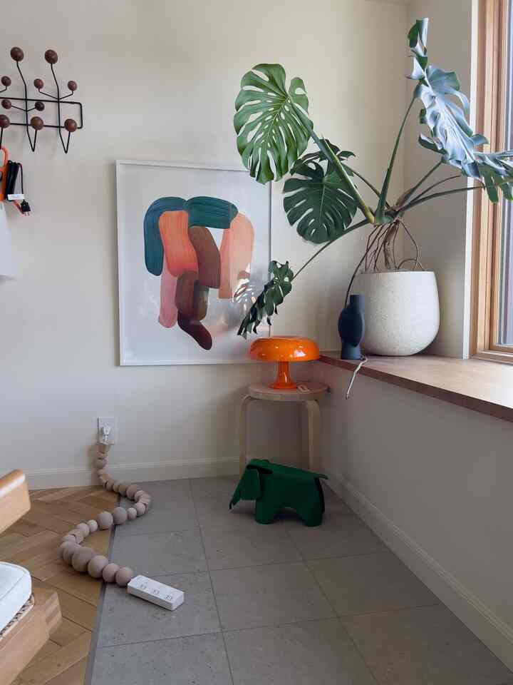 ナチュラルカラーのリビングコーナー、オレンジのライトとグリーンの植物が配置された雰囲気のある空間