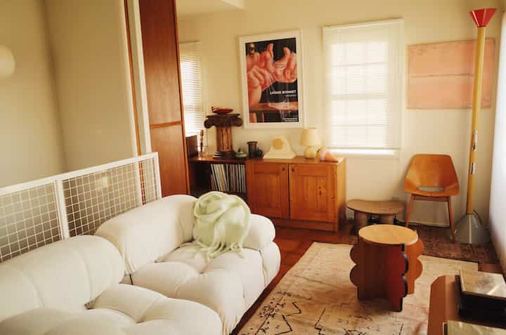 A cozy living room with natural colors and wood tones featuring a white sofa and wooden coffee tables in vintage style