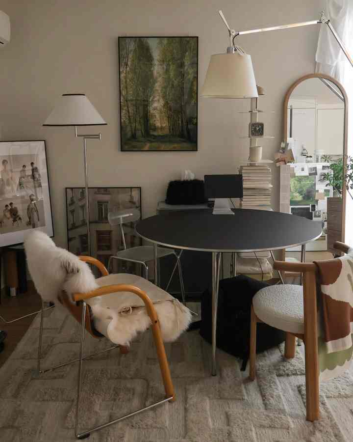 ナチュラルトーンと黒い丸テーブルのある8畳ワンルームのリビング、木製チェアや額縁、フロアランプが配置された雰囲気のあるインテリア