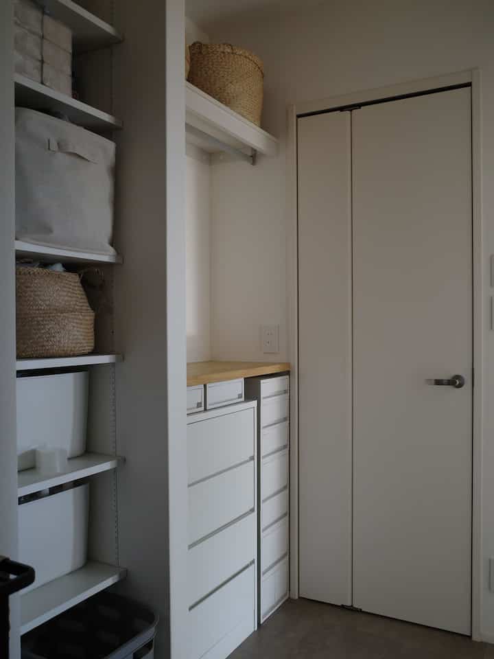 白とナチュラルカラーが調和したコンパクトなクローゼットと収納が配置された清潔感のある脱衣・ランドリースペース