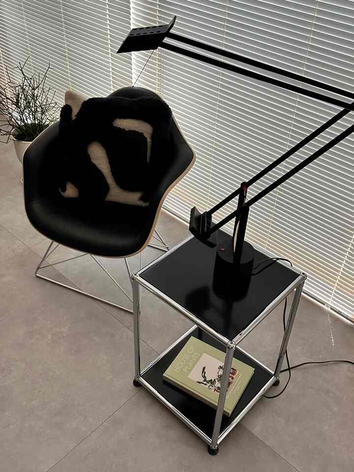 白と黒のトーンの小さな部屋、黒のアームチェアとサイドテーブルにフロアランプが配置されたミニマルなインテリア