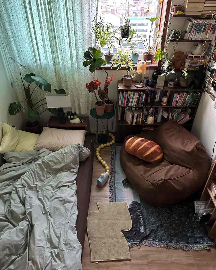 木目調とナチュラルカラーの寝室、ブラウンのビーズクッション、たくさんの植物と本棚が配置された雰囲気のあるインテリア