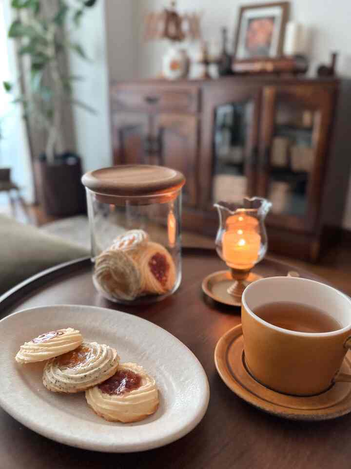 温かみのあるブラウンの木目調ダイニング、紅茶とクッキー、落ち着いた雰囲気のキャンドルが置かれた空間