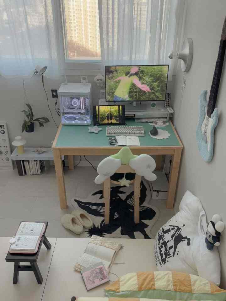 ホワイトと木目調が調和したワンルームの寝室兼ホームオフィス、ミッドセンチュリーモダンのデスクとモニターが配置された居心地の良い空間