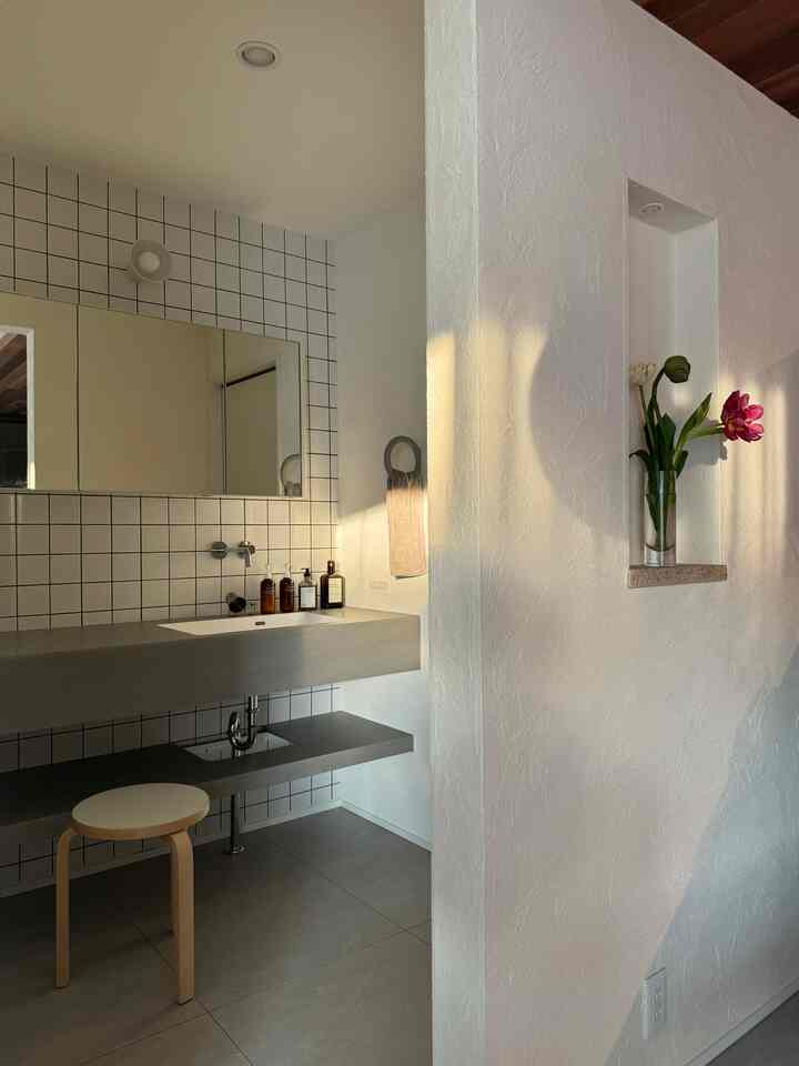 白とグレー調のバスルーム、アルテックのスツールとタイル壁、自然光が差し込むナチュラルモダンなインテリア