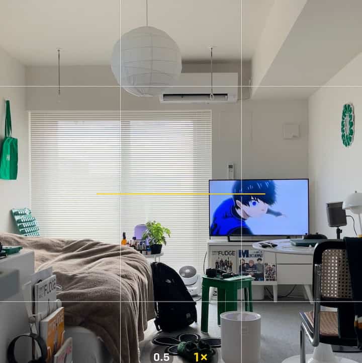 ホワイトとグリーンのトーンの一人暮らし向けの狭い部屋、テレビとデスクが配置された北欧スタイルのコンパクトなリビング