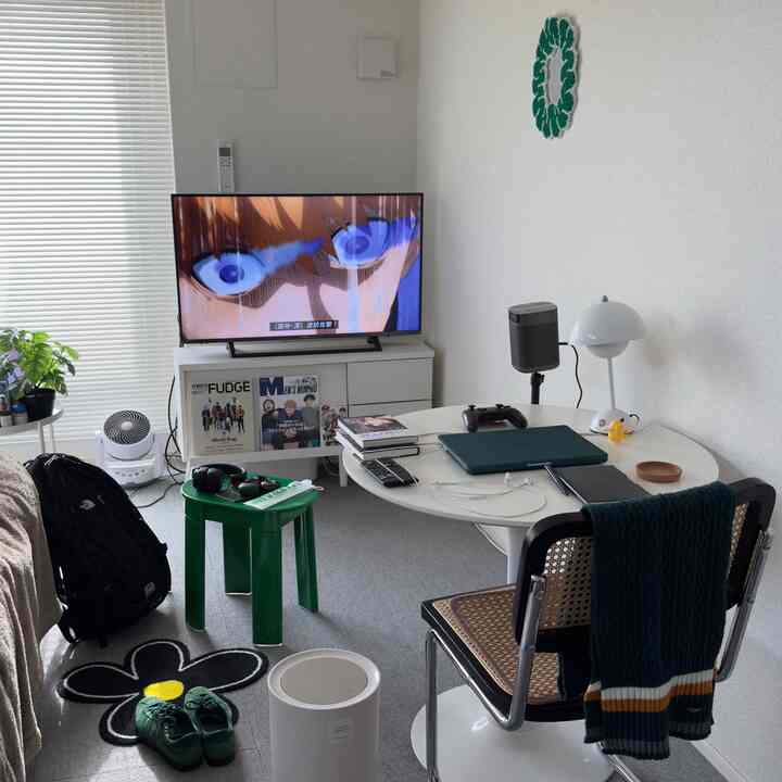 Modern compact living room in white and green tones featuring TV and gaming accessories