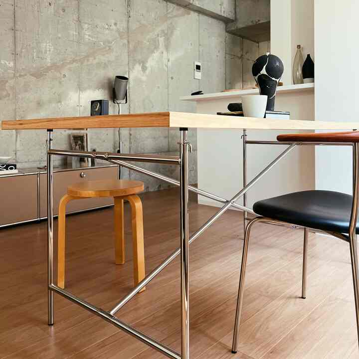 ウッドトーンとシルバークロームが調和したモダンなリビング、木製のダイニングテーブルとスツールが配置された落ち着いた雰囲気のインテリア