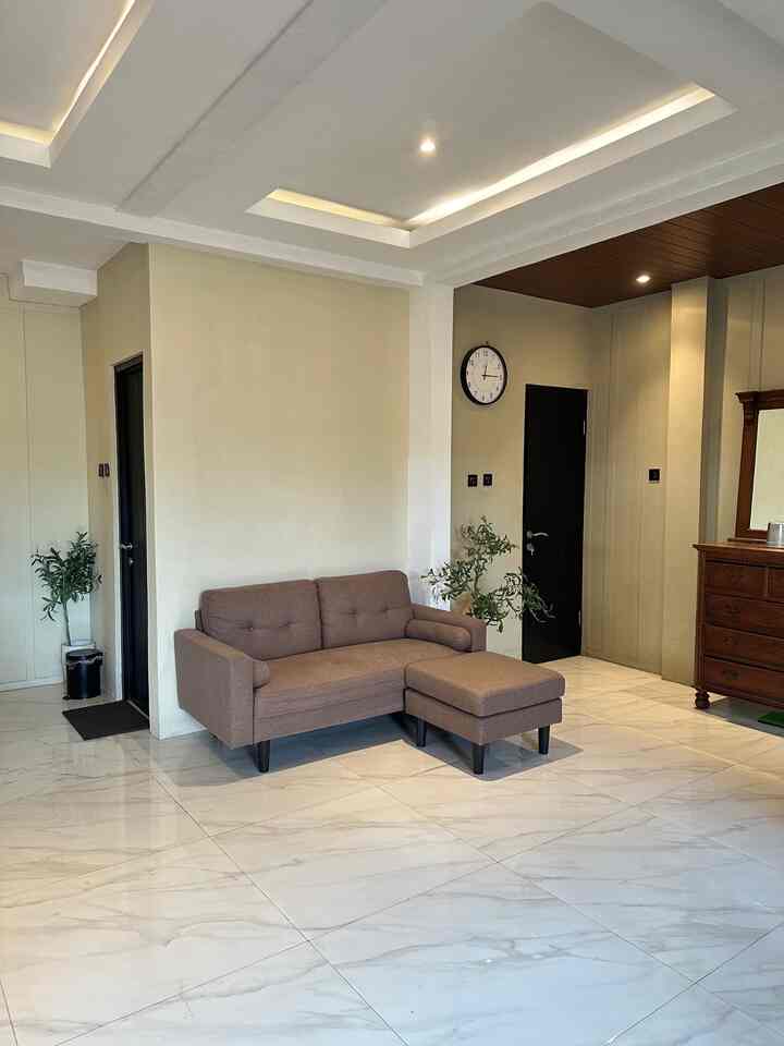White walls and floor with a brown sofa and olive plants in a simple two-person living room space