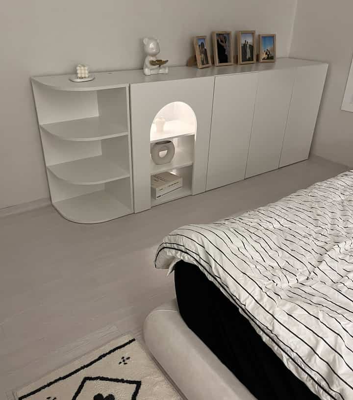 ホワイトトーンの寝室、壁一面に配置されたすっきりとした収納キャビネットとベッドがあるミニマルなインテリア